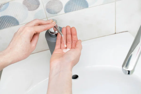 stock image Washing hands with liquid soap in a bottle under the faucet in the bathroom. An image on the theme of hygiene, personal care and cleanliness for your design or creative decoration.