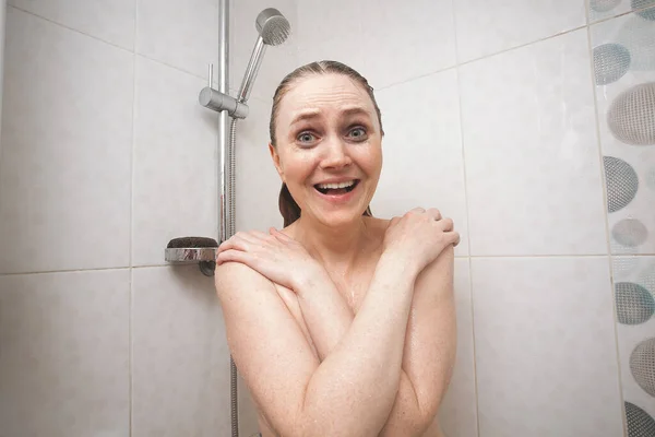 在浴室里 一个有着金发和睫毛膏涂在脸上的有趣而性感的微笑女孩赤身裸体地站在浴室里 一个关于纯洁 健康和好心情的形象 图库图片