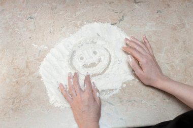 Kadın masadaki una parmaklarıyla gülen bir yüz çizdi. Yaratıcı tasarımın ya da dekorasyonun için canlı çekim.