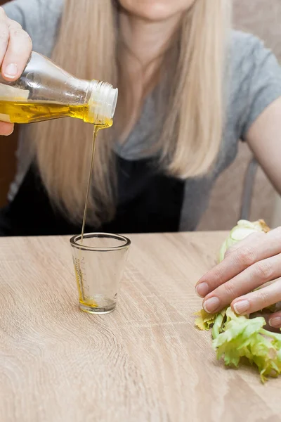女性はオリーブオイルを計量カップに注ぎます 木製のテーブルの上にセロリがあります あなたの健康的な食品の創造者のための画像 — ストック写真