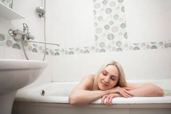 一个金发碧眼的漂亮的微笑女孩坐在浴室里洗澡时 关于清洁和照顾你自己和你的身体的形象 — 图库照片