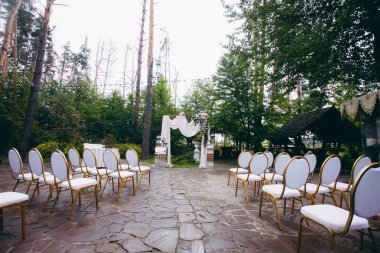 Yeni evliler için şık bir düğün kemeri ve parktaki tören konukları için sandalyeler. Tasarımınız veya çizimleriniz için yaratıcı resim.