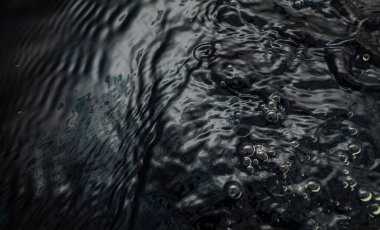 Crumpled textured dark fabric lies in the water. Abstract image with beautiful highlights for your creative design or stylish illustrations.