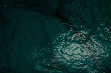 A dark green fabric with folds lies underwater with waves and splashes. Image for your creative design or stylish illustrations.