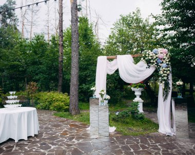 Kumaş ve doğal çiçeklerle süslü bir düğün kemeri. Şampanya kadehleri piramidi olan bir masa. Tasarımınız veya çizimleriniz için yaratıcı resim.