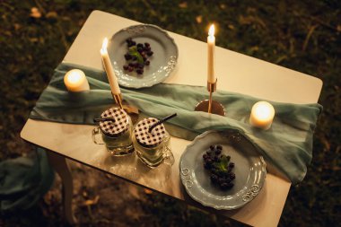Mumlar, dut tabakları ve bardaklar gece vakti bir bezle şenlikli, dekoratif bir masada duruyor. Yaratıcı tasarımın ve çizimlerin için resim.