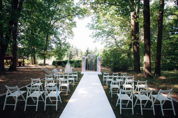 stock image Stylish wedding arch for the newlyweds and chairs for the guests of the ceremony, in the park. Creative image for your design or illustrations.