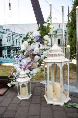 Gündüzleri şehirde taze çiçekler, fenerler ve mumlarla süslenmiş yeni evliler için şık bir düğün kemeri. Düğün dekoru ve töreniyle ilgili görüntü.