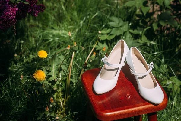 在一个盛开的花园里 一对新娘的鞋子在凳子上和结婚戒指上的浪漫的婚礼布置 为您的创意设计或插图的图像 — 图库照片