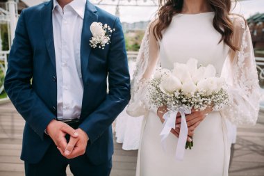 Mavi takım elbiseli damat ve ellerinde buket olan beyaz elbiseli gelin. Tasarımınız veya yaratıcı çizimleriniz için düğün kompozisyonu.