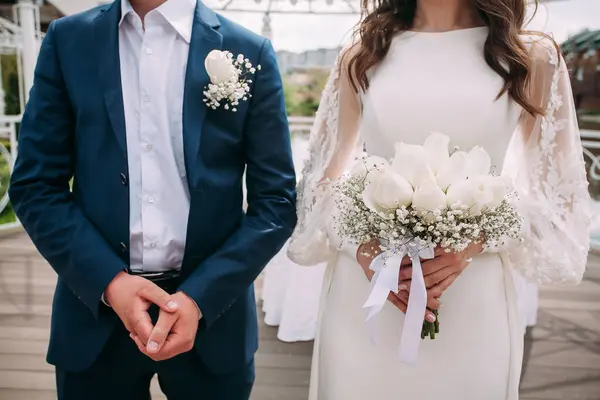 Mavi takım elbiseli damat ve ellerinde buket olan beyaz elbiseli gelin. Tasarımınız veya yaratıcı çizimleriniz için düğün kompozisyonu.