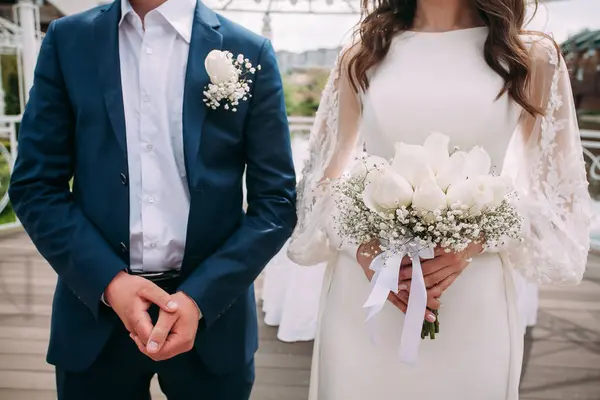 新郎穿蓝色西服 新娘穿白色连衣裙 手里拿着花束 为你的设计或创意插图准备婚纱 免版税图库图片