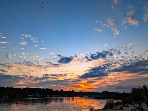 Nehir üzerindeki büyüleyici günbatımı manzarası, portakalı yansıtan ışık suyu. Bulutlu mavi gökyüzü. Kara bulutlu yaz gökyüzü, bulutlu ve temiz hava fotokopi uzayıyla.
