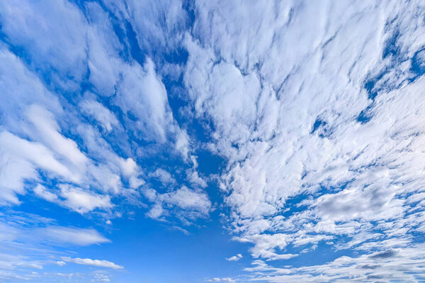 Вентилятор перистых облаков разворачивается на голубом небе. Панорамный вид на широкоугольный пейзаж. Всеобъемлющее впечатление бесконечных возможностей, свободы и полета.