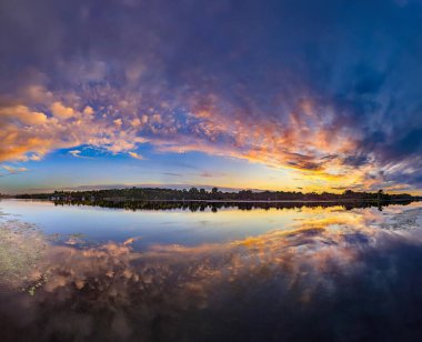 Gökyüzünde muhteşem bir günbatımı ve su nehrine yansıyan ılık ve serin tonlardan oluşan yumuşak pembe bulutlar tuvalde görüntüler canlandırıyor. Peri muamması derin, muhteşem, karanlık, destansı gökyüzü. Dramatik akşam ışığı ve ateşli turuncu menekşe gün batımı. Mavi arkaplanda sarı ateş.