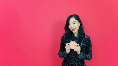 Güzel, genç, gülümseyen, gece elbisesi giyen, el saati tutan mutlu bir kadın. Çalışma alanını bir kenara bırak. Sade kırmızı arka plan stüdyo resmine izole edilmiş. Mutlu yıllar 2023 Kutlama Konsepti