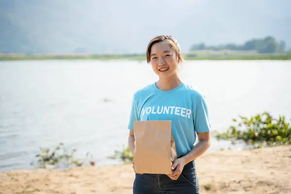 Retrato Mulher Jovem Vestindo Camiseta Voluntária Segurando Saco Doação Olhando — Fotografia de Stock