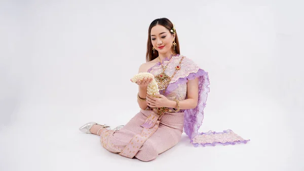 亚洲妇女身穿带有泰国文化特征的典型传统泰式服装 手持花环 坐在那里 与白色背景隔离 — 图库照片