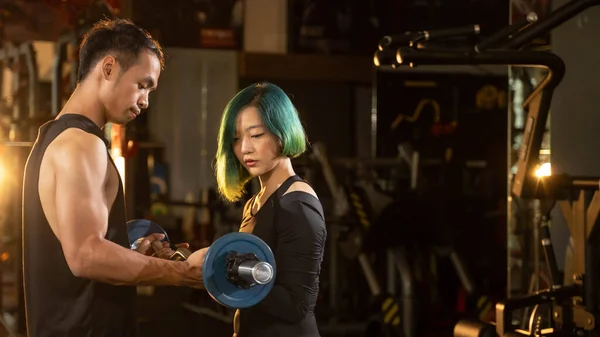 man and woman with barbell flexing muscles in gym. Banner size with copy space.