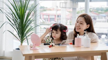 Mutlu anne, sevimli kızının makyajla oynamasını, saç yuvarlatıcılarıyla göz farı sürmesini, evdeki güzellik seansında birlikte vakit geçirmenin tadını çıkarmasını izliyor..