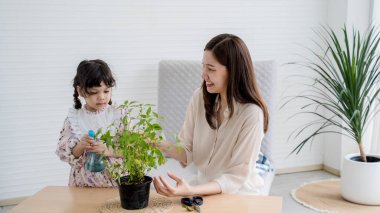 Anne ve kızı kapalı alanda saksıları sularken birbirlerine bağlanıyorlar, çevre bakımını öğretiyorlar ve bahçe işlerini rahatlatmanın keyfini çıkarıyorlar..
