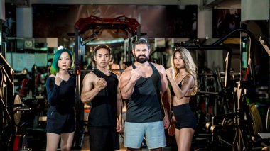 Sağlıklı yaşam tarzı ve takım çalışması için kendine güvenen fitness takımı, birlik, güç ve motivasyon sembolü olarak yumruklarını kaldırıyor..