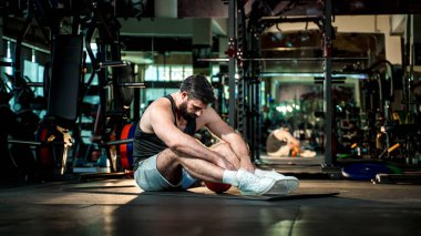 İlaç topuyla yapılan yoğun antrenmandan sonra spor salonunda dinlenen yorgun adam azmi, fiziksel yorgunluğu, zihinsel odaklanmayı ve atletik bağlılığı simgeliyor..