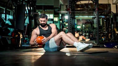 Modern spor salonunda Rus büküm egzersizi yapan odaklanmış bir adam, temel kuvvet eğitimi, sağlıklı yaşam tarzı, fitness kararlılığı ve vücut koşullandırması..