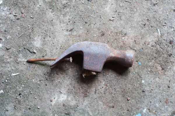 Gri desenli çimento arka planında sapı olmayan kırık bir çekiç..