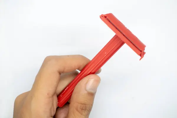 Beyaz arka planda bir jileti tutan el.