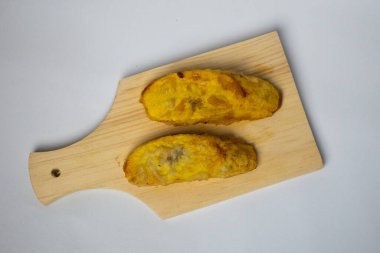 Fried bananas on a wooden cutting board on a white background clipart