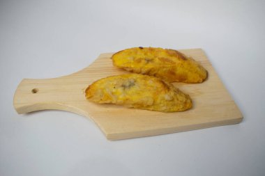 Fried bananas on a wooden cutting board on a white background clipart