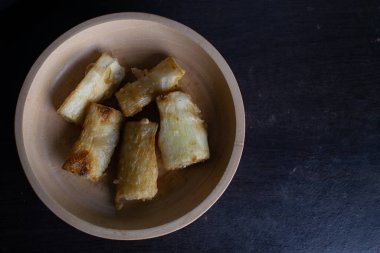 Ahşap bir kasede servis edilen kızarmış manyok yemeği.