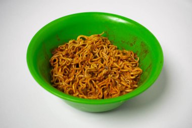 İçinde kızarmış erişte olan yeşil plastik bir kase. Arkaplan beyaz.