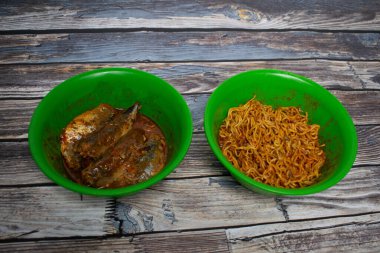 Green plastic bowl filled with sardines and fried noodles. Serving simple home cooking but appetizing. clipart