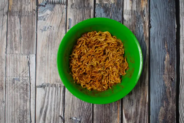 İçinde kızarmış erişte olan yeşil plastik bir kase. Basit ev yemekleri ama iştah açıcı..