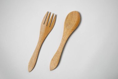 Bir çift çevre dostu ahşap çatal ve kaşık, beyaz arka plana yerleştirilmiş..