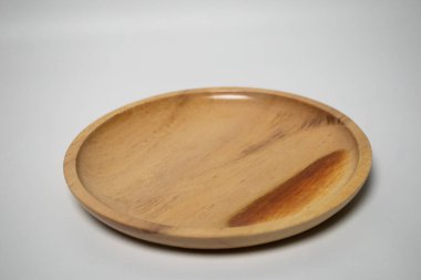 Yuvarlak ahşap bir tabak, pürüzsüz bir kaplama, beyaz arka plan üzerine yerleştirilmiş..