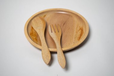 Minimalist ahşap sofra takımı bir kaşık, tabak ve çatalı düz konumda sergiliyor..