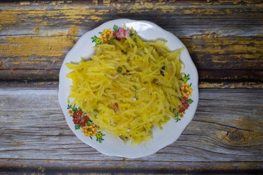 Sarı papaya kızartması, özenle baharatlı ve güzel bir çiçek tabağında sunuluyor..