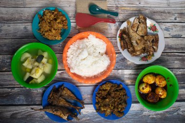 Ana yemek, kızarmış balık, baharatlı yumurta, çorba, tavuk derisi ve yumurtalı erişteyle çevrili beyaz pirinçtir..