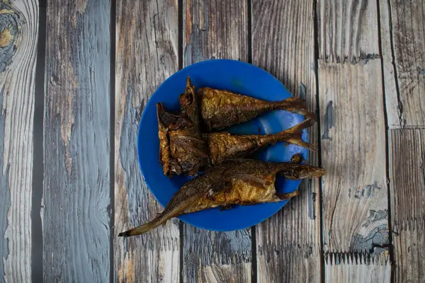 Mavi bir tabakta servis edilen kızarmış balık geleneksel bir ev yemeği olarak sunulmaya hazır..