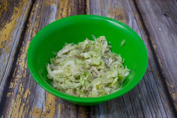 Ilık öğütülmüş lahana, parlak yeşil bir plastik kasede servis edilir..