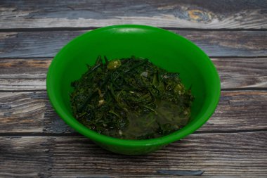 Bir kase kızarmış eğreltiotu taze yapraklarla yeşil plastik bir kasede filizlenir..