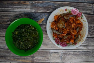 Bir tabak baharatlı karides ve bir kase kızarmış sebze kırsal ahşap masada..