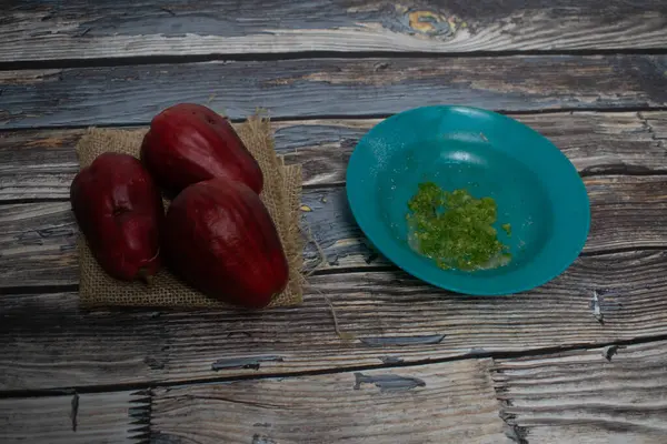 Kır evinde yeşil bir tabakta baharatlı yeşil biber soslu üç guava.