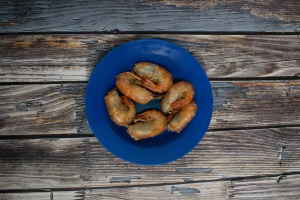 Pişmiş karides mavi bir tabakta servis edilir, kırsal deniz ürünleri yemeği için mükemmeldir..