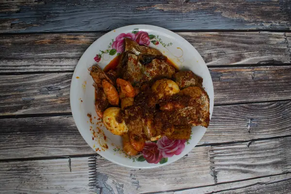 Baharatlı karidesler, haşlanmış yumurtalar, kızarmış balıklar ve çiçek tabağında tempeh içeren geleneksel bir yemek..