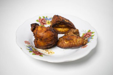 Kızarmış tavuk parçaları çiçek desenli bir tabağa konur. Lezzetli bir ev yemeği olarak servis edilmeye hazırdır..