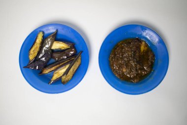 Geleneksel acı biber soslu basit ama lezzetli bir kızarmış patlıcan yemeği, mavi plastik tabakta servis edilir..